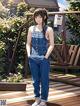 A woman in overalls standing on a wooden deck.