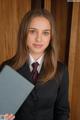 A woman in a suit and tie holding a book.