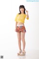 A woman in a yellow shirt and floral shorts posing for a picture.