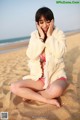 A woman sitting on the sand on a beach.