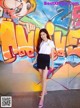 A woman standing in front of a graffiti covered wall.