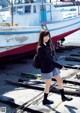 A woman in a school uniform standing next to a boat.