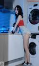 A woman standing in front of a washing machine in a kitchen.